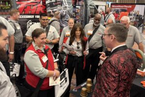 Joe Turner performing cups and balls for a crowd of attendees at a trade show booth in Memphis.